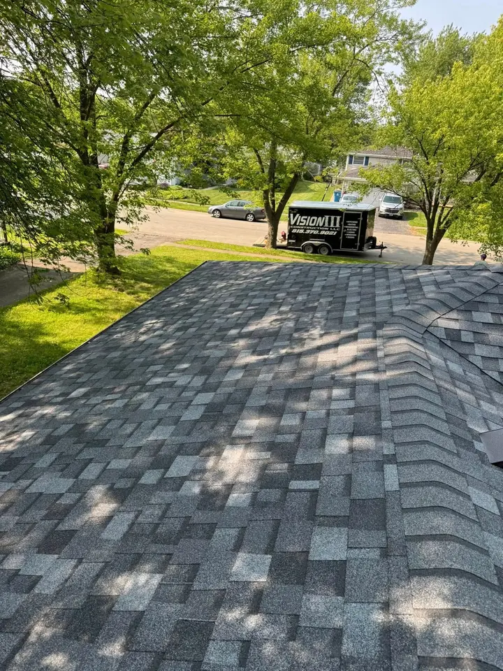 Gray shingle roof with ridge vents and trees beyond